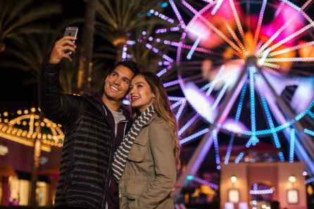 young couple takes selfie by ferris wheel